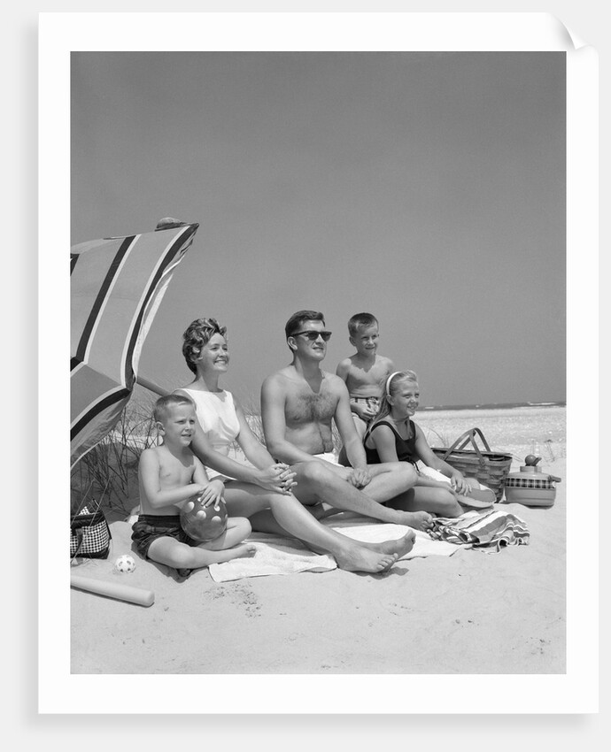 1960s Family Portrait Mother Father Daughter And Two Sons Sitting On Beach Under Umbrella by Anonymous