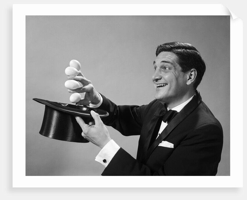 1960s Profile Magician Man Pulling 4 Eggs Out Of Hat Holding Them Between Fingers by Anonymous