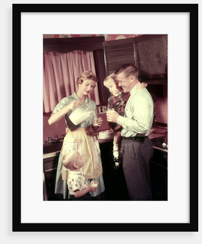 1950s Family In Kitchen Mother Pouring Milk From Pitcher For Dad And Kids by Anonymous