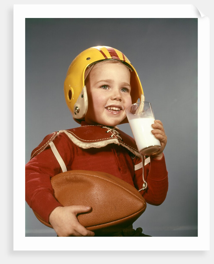 1950s 1960s Boy Drinking Glass Milk Wearing Football Helmet Shoulder Pads by Anonymous