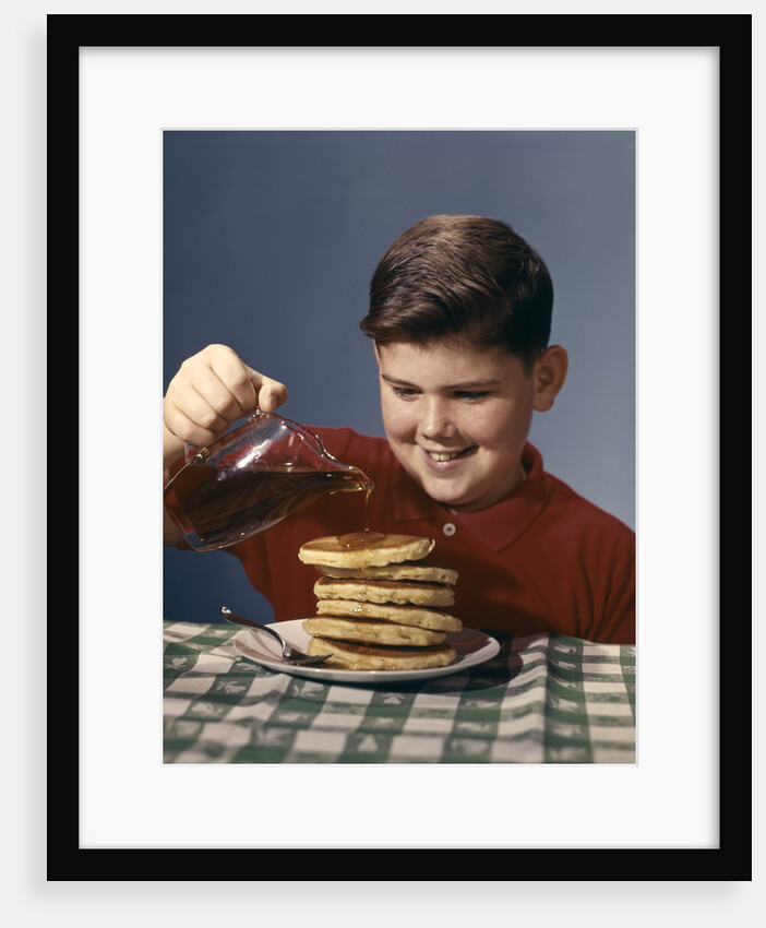 1950s 1960s Boy Pouring Syrup On Breakfast Pancakes by Anonymous