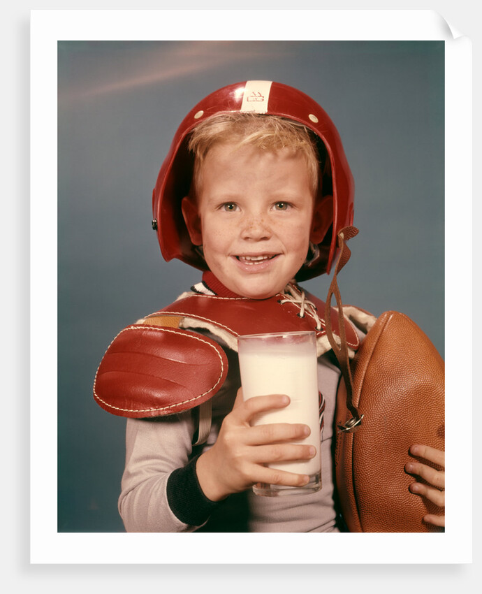 1960s Boy Wearing Red Helmet Football Shoulder Pads Holding Glass Milk and Football by Anonymous