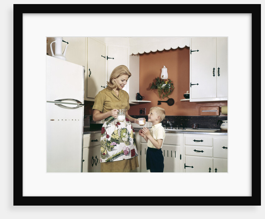 1970s Mother Handing Glass Of Milk To Son In Kitchen by Anonymous