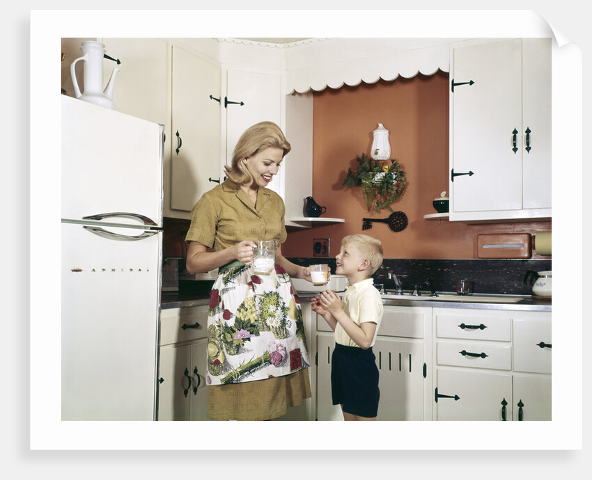 1970s Mother Handing Glass Of Milk To Son In Kitchen by Anonymous