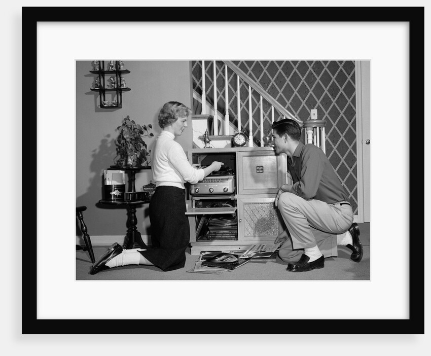 1950s Teenage Couple Playing Hi-Fi Records On Console Phonograph In Living Room by Anonymous