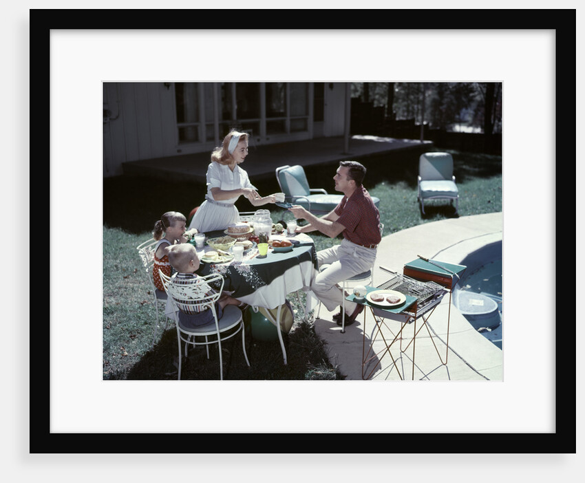 1950s Family In Backyard Having Picnic From Grill Near Swimming Pool by Anonymous