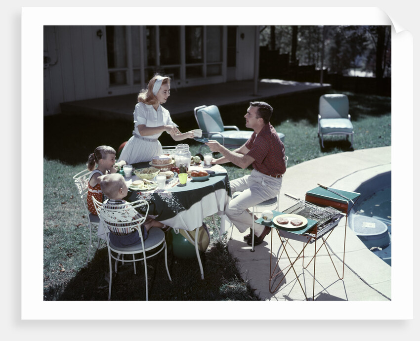 1950s Family In Backyard Having Picnic From Grill Near Swimming Pool by Anonymous