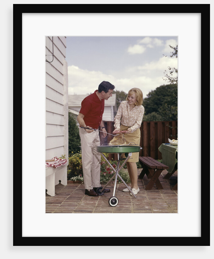 1960s Couple Man Woman Grilling Steak On Backyard Patio Bar-B-Cue Charcoal Grill by Anonymous