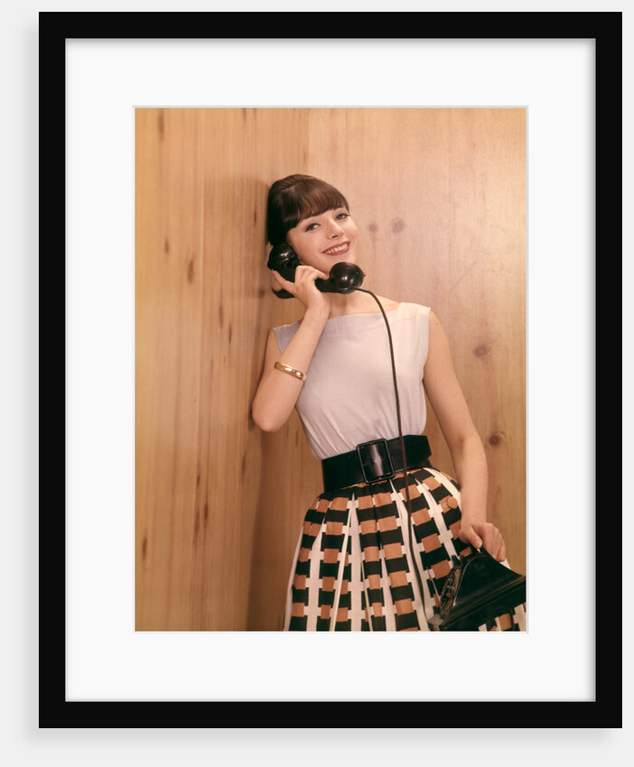 1950s 1960s Brunette Woman Talking Telephone Leaning Against Wood Panel Wall by Anonymous