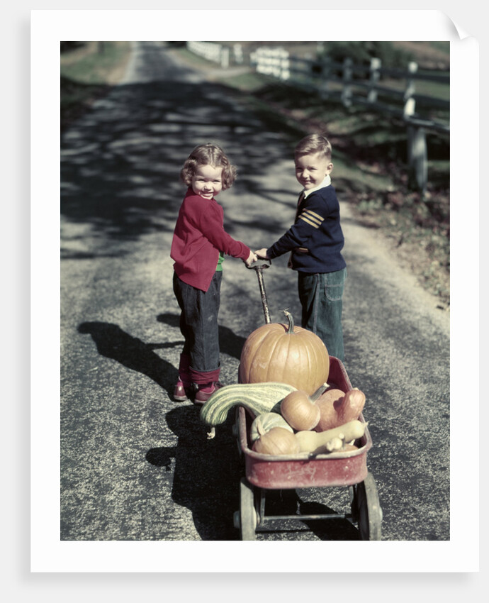 1950s Kids In Blue Jeans Pulling Red Wagon Full Of Pumpkins by Anonymous