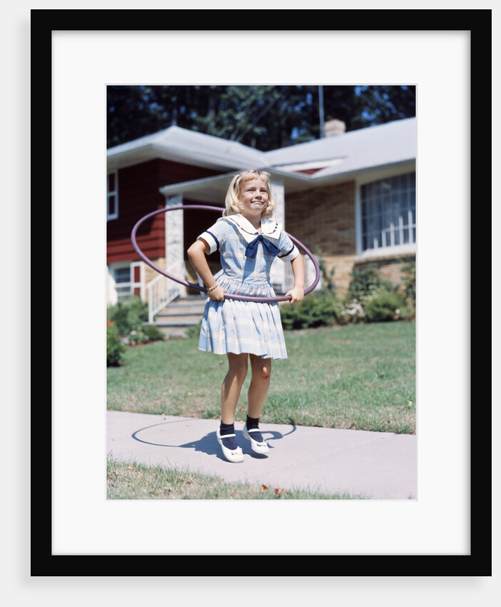1950s 1960s Young Girl Playing With Hula Hoop Outside On Suburban Sidewalk In Sailor Style Dress by Anonymous