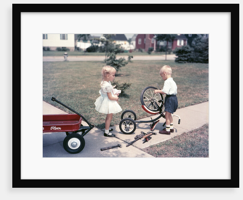 1950s Little Girl Sister Holding Doll Watching Little Boy Brother Repair Tricycle by Anonymous