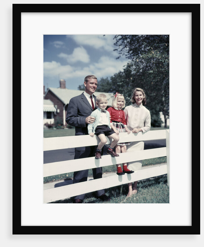 1950s 1960s Family Portrait Mother Father Daughter Son At White Fence Of Suburban Home by Anonymous