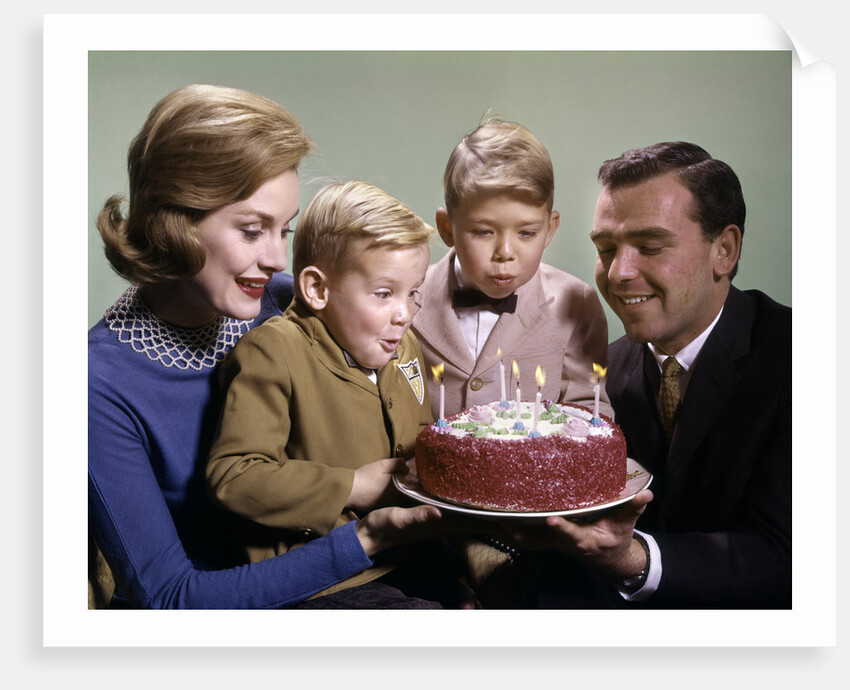 1960s Mother And Father Holding Birthday Cake And Sons Blowing Out Candles by Anonymous