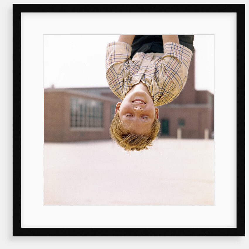 Red Haired Boy Hanging Upside Down In Elementary School Yard by Anonymous