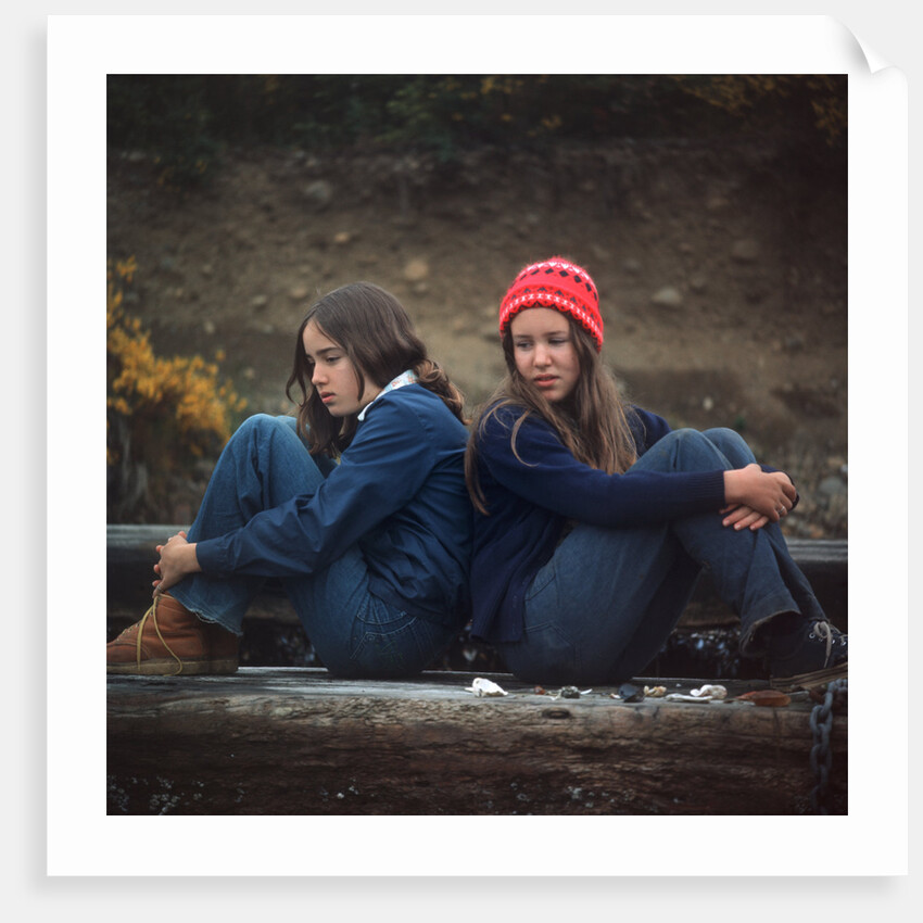 1970s Two Sad Serious Teenage Girls Sitting Back To Back Outside by Anonymous