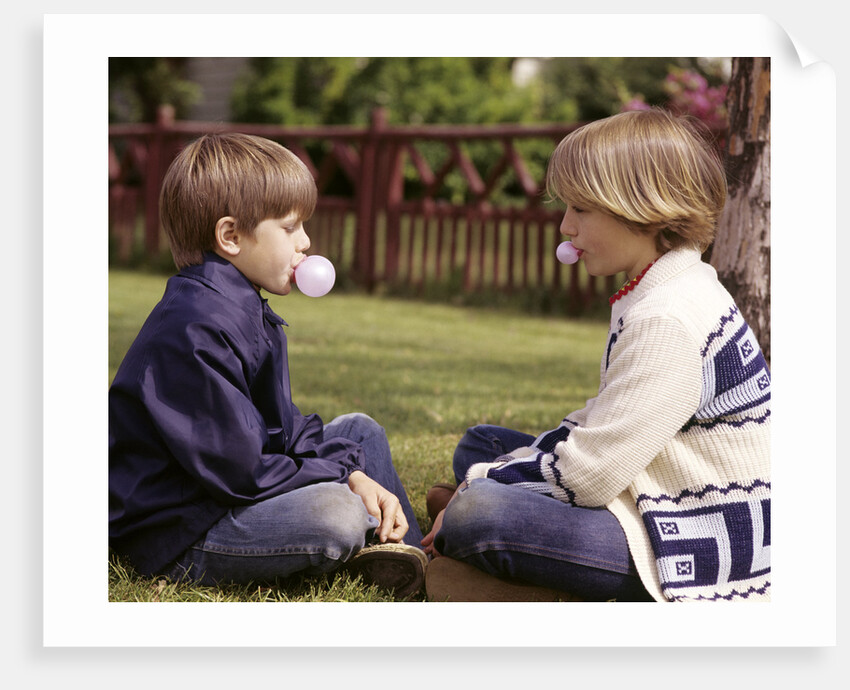 1970s Girls Sit Face To Face Blowing Pink Bubbles With Bubble Gum by Anonymous