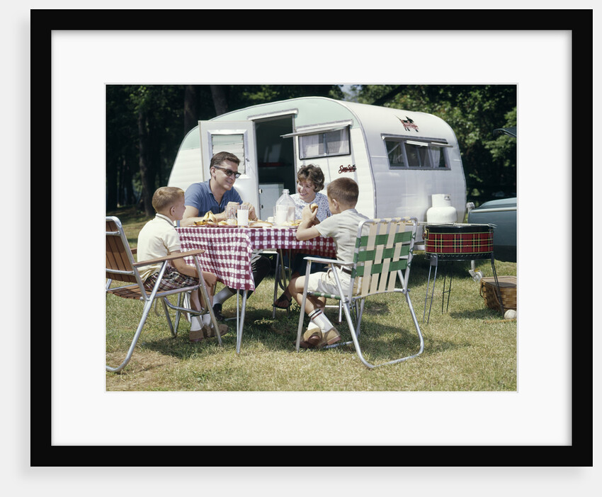 1960s Family Sitting In Lawn Chairs At Picnic Table Beside Camping Trailer by Anonymous