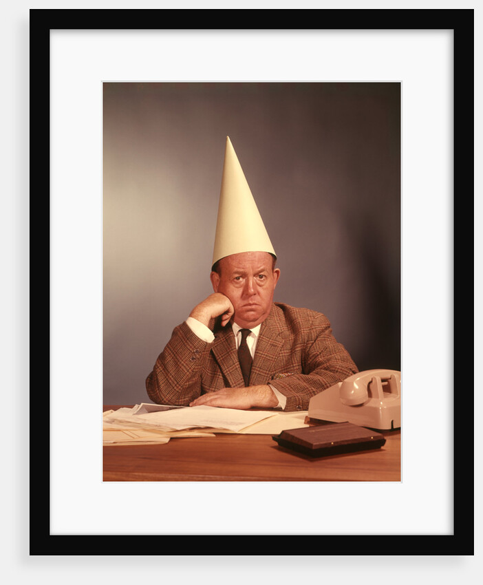 1960s Sad Depressed Businessman Wearing Dunce Cap by Anonymous