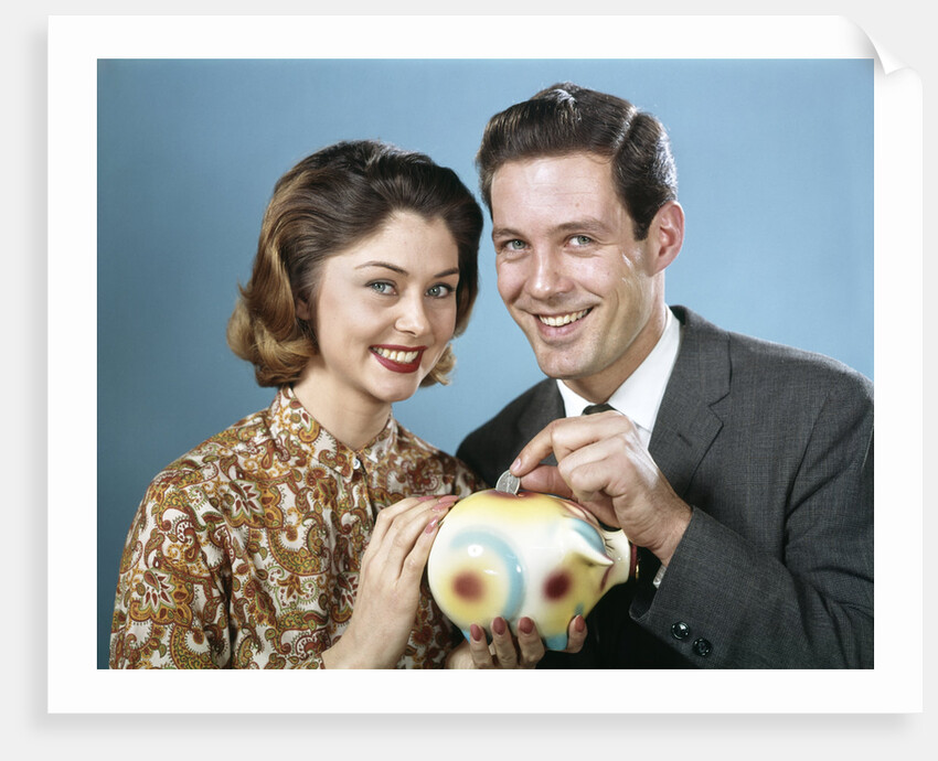 1950s 1960s Young Couple Man And Woman Put Quarter In Savings Piggy Bank by Anonymous