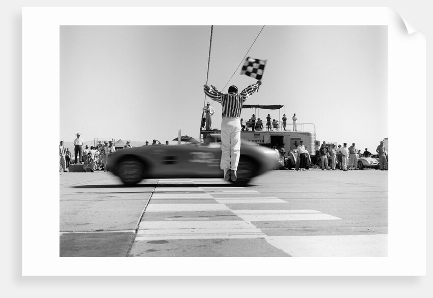 1960s Man Jumping Waving Checkered Flag As Winning Sports Car Crossing The Finish Line by Anonymous