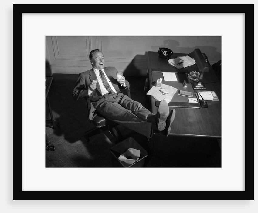 1950s Man Businessman Salesman Eating Lunch In Office With Feet Resting Up On Desk by Anonymous