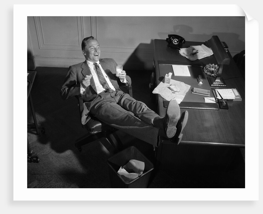 1950s Man Businessman Salesman Eating Lunch In Office With Feet Resting Up On Desk by Anonymous