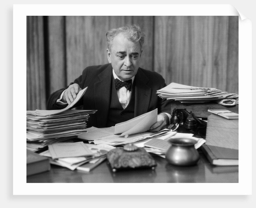 1920s 1930s Elderly Executive Man Sitting At Desk Looking Through Papers by Anonymous
