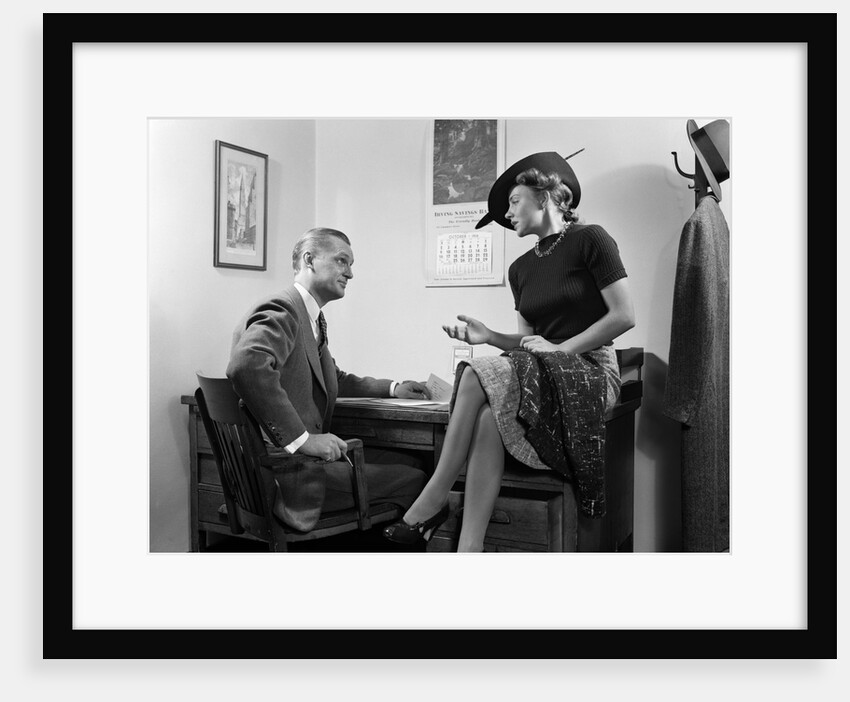 1940s Woman Sitting On Desk Hat Skirt Hand Gesture Talking Flirting With Man by Anonymous