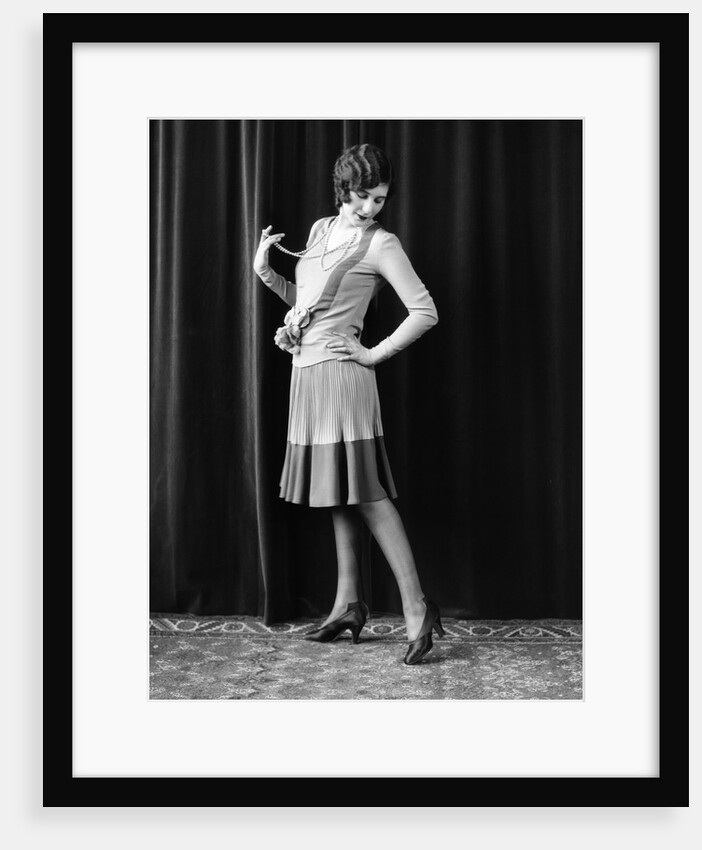 1920s Flapper Woman Posing Hand On Hip Holding String Of Pearls Stretching Leg Checking Hosiery Seams by Anonymous