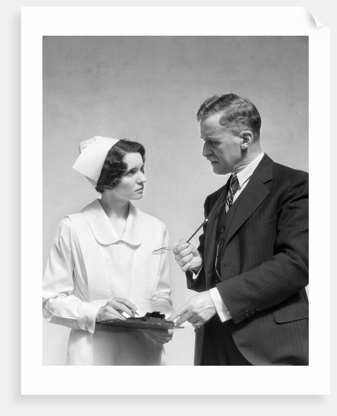 1930s Doctor In Suit And Necktie Confers With Nurse In Uniform And Cap Holding Clipboard Chart by Corbis