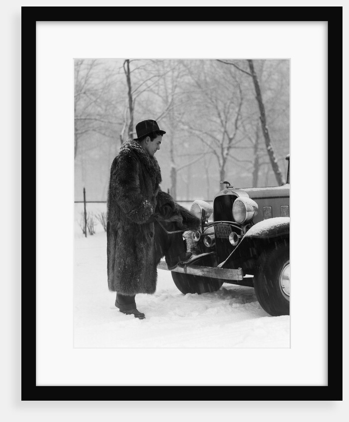1930s Man In Hat And Raccoon Fur Coat Standing Foot On Bumper Of Chevrolet Roadster Stalled In Snow Storm by Anonymous