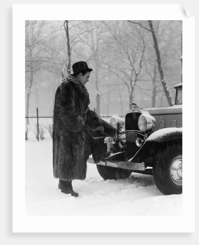 1930s Man In Hat And Raccoon Fur Coat Standing Foot On Bumper Of Chevrolet Roadster Stalled In Snow Storm by Anonymous