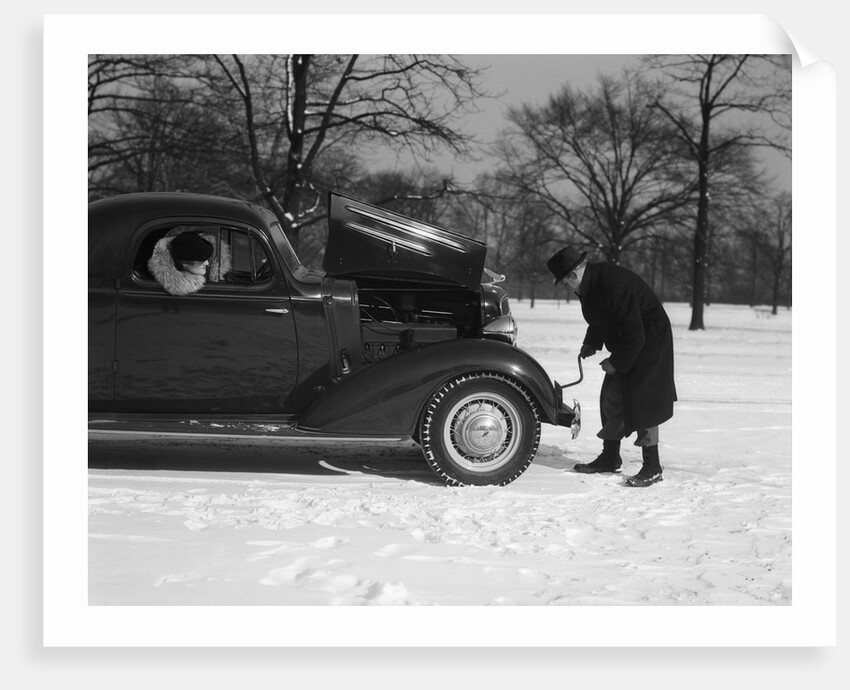 Woman Passenger Watching Man Motorist Try To Crank Start A Chevrolet Coupe Stalled In Snow by Anonymous