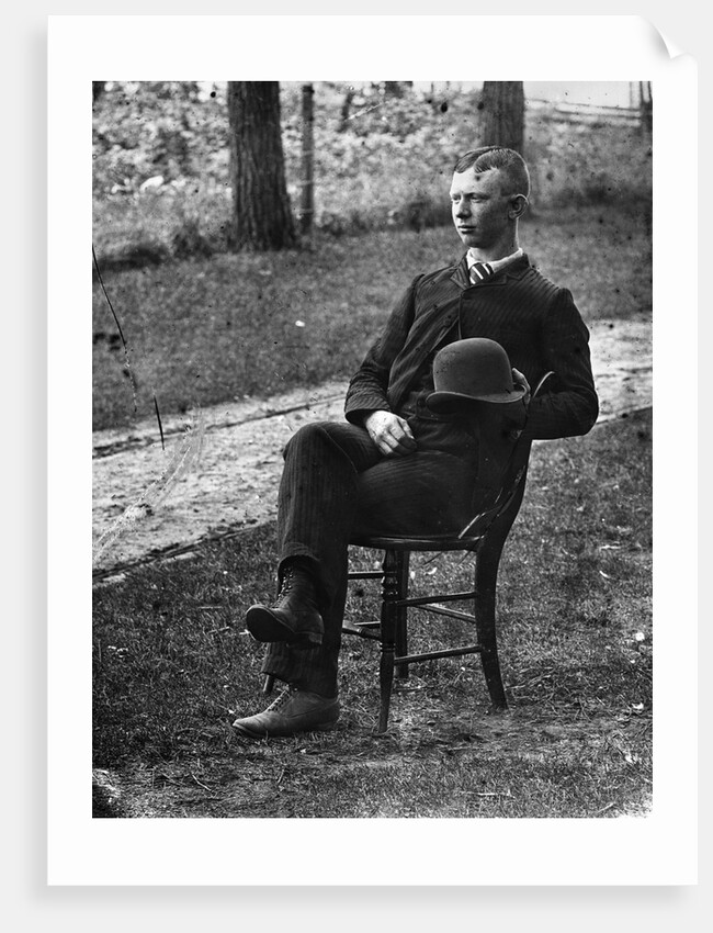 1890s 1900s Side View Of Man Wearing Suit Seated On Chair Outside Holding Bowler Hat by Anonymous