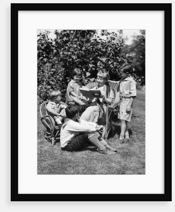 1920s Older Woman Grandmother Sitting In Wicker Chair Reading Book To Four Boys Girls Grandchildren by Anonymous