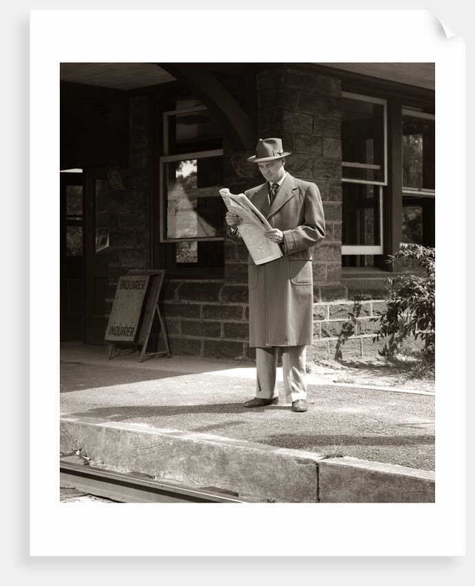 1950s Businessman On Railroad Station Platform Reading Newspaper Waiting For Train by Anonymous