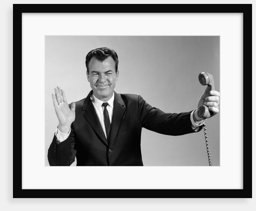 1960s Businessman Holding Telephone At Arms Length With Expression Of Disgust Or Rejection by Anonymous