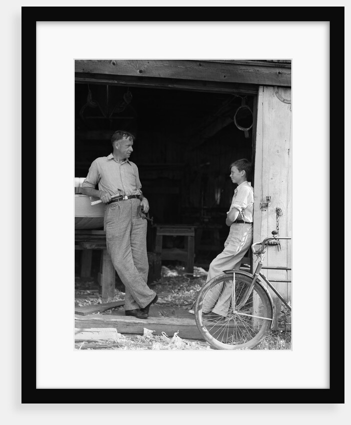 1930s Man Father Holding Hand Tools Talking To Boy Son Leaning In Doorway Of Boat Shed by Anonymous