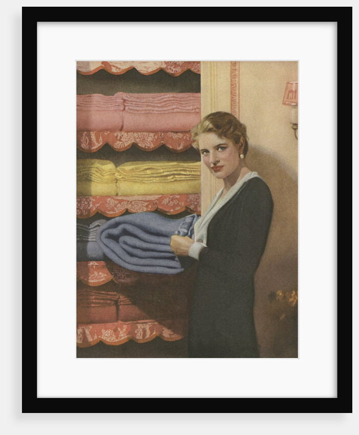 Woman puting away blanket in linen closet by Anonymous