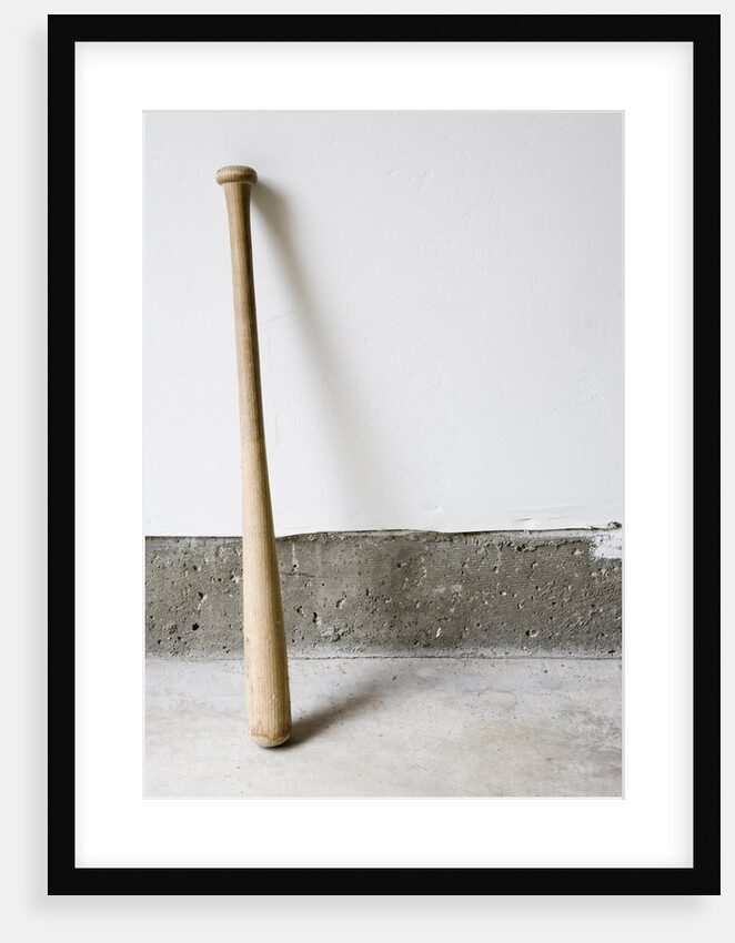 Detail of wooden baseball bat against white and concrete wall. by Anonymous