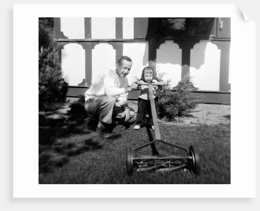 A father show his two year old daughter how to mow the lawn, ca. 1956 by Anonymous