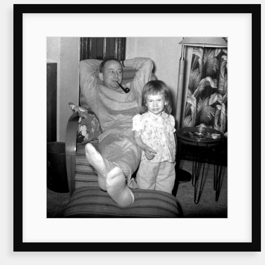 Dad relaxes and smokes his pipe with his four year old daughter, ca. 1958 by Anonymous