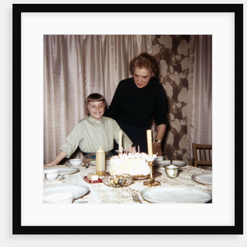 Nine year old girl is about to blow out the candles on her while her mom watches, ca. 1962 by Anonymous