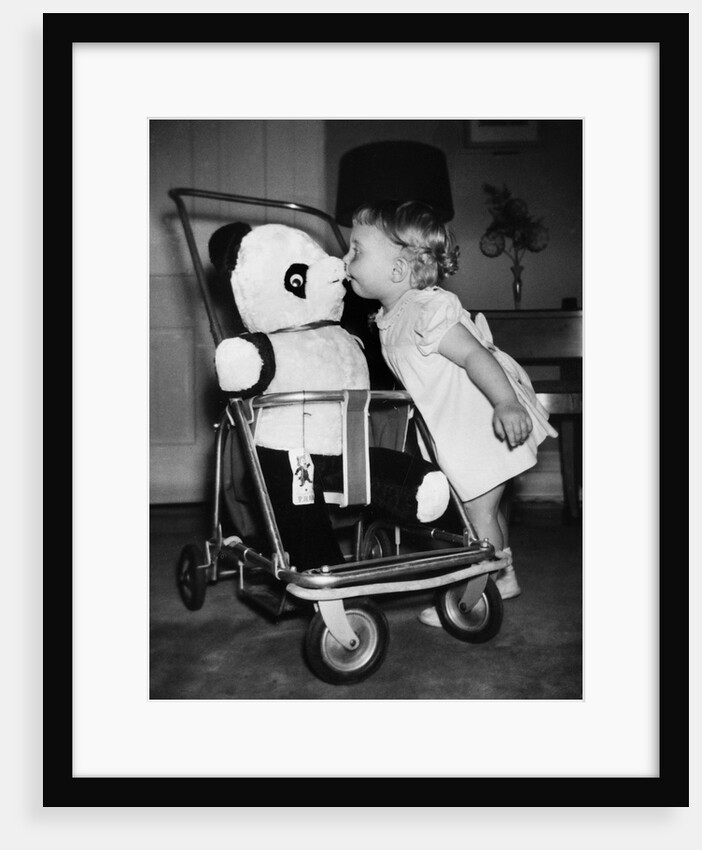 A two year old girl kisses a stuffed panda on the nose, ca. 1955 by Anonymous