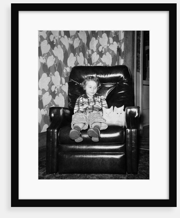 Young girl sits with her two cats in a leather chair, ca. 1960 by Anonymous