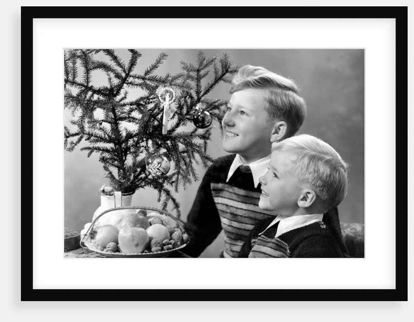 Two brothers look at a candle on a Christmas tree in Germany, ca. 1950 by Anonymous