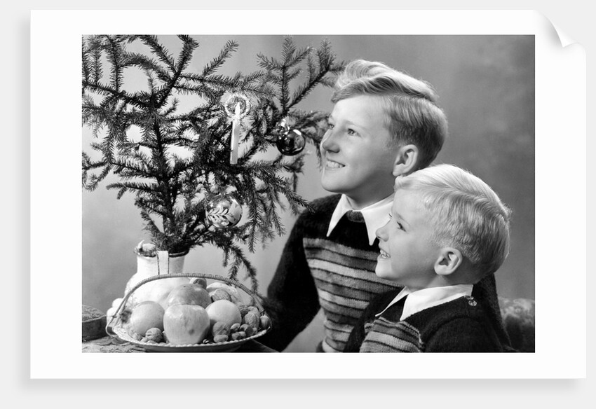 Two brothers look at a candle on a Christmas tree in Germany, ca. 1950 by Anonymous