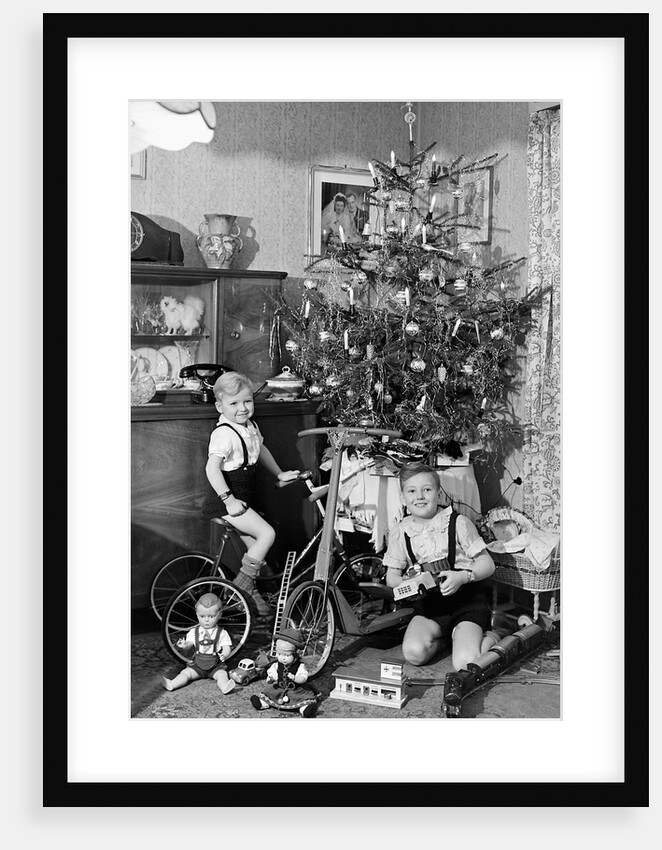 Two brothers are shown with their toys under the Christmas tree in Germany, ca. 1949 by Anonymous