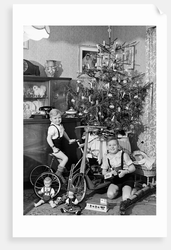 Two brothers are shown with their toys under the Christmas tree in Germany, ca. 1949 by Anonymous